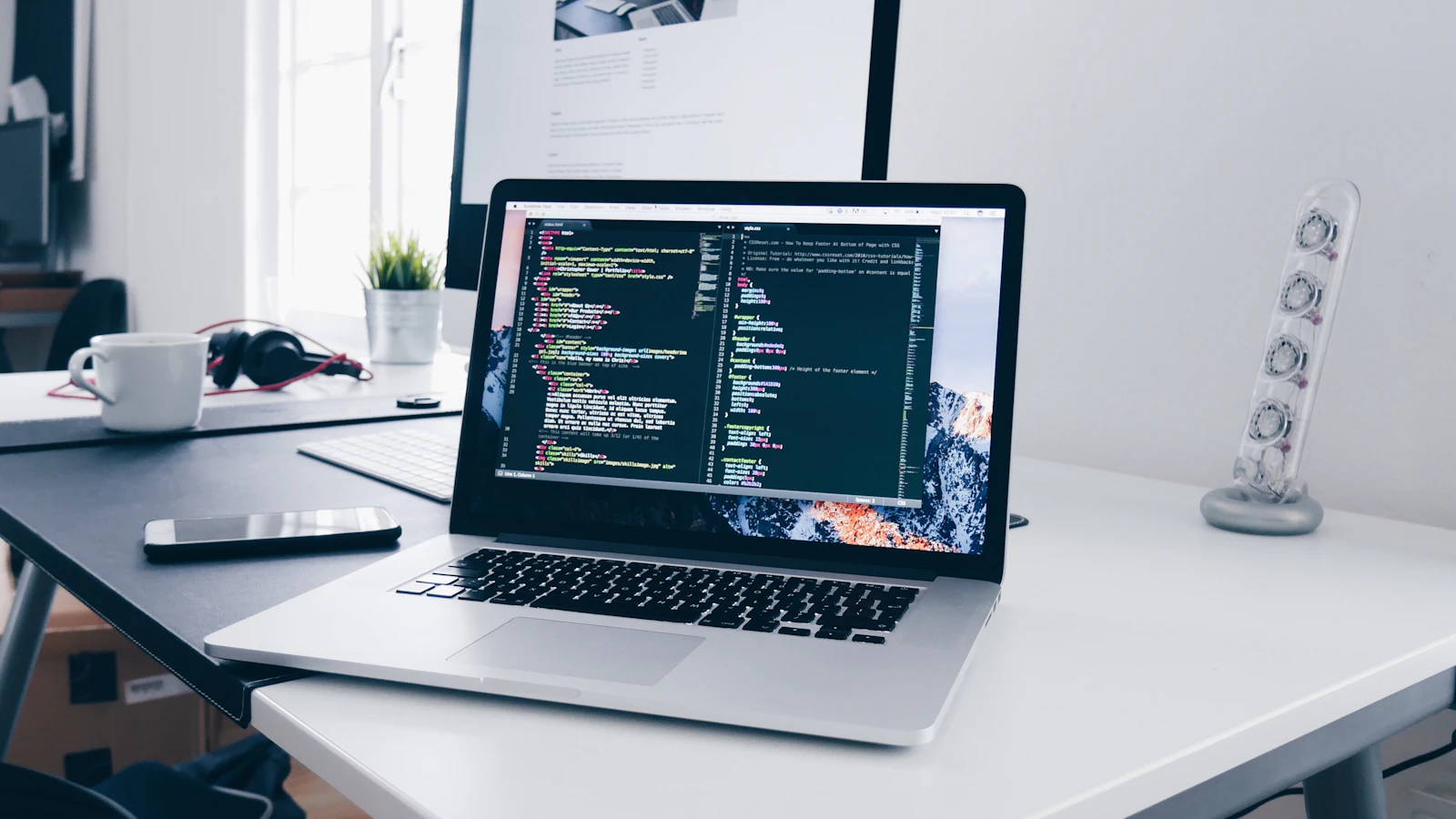 A laptop showing lines of code on a busy desk